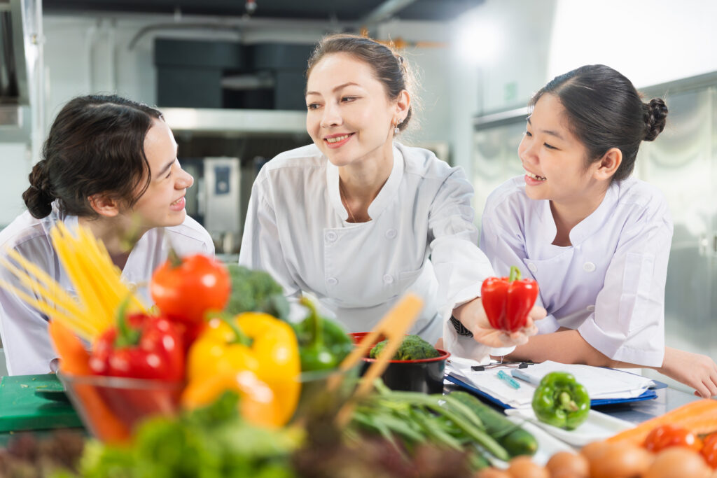 chef-students-learning-culinary-skills-kitchen-women-preparing-fresh-ingredients-cooking-class-professional-chef-mentoring-young-cooks-kitchen