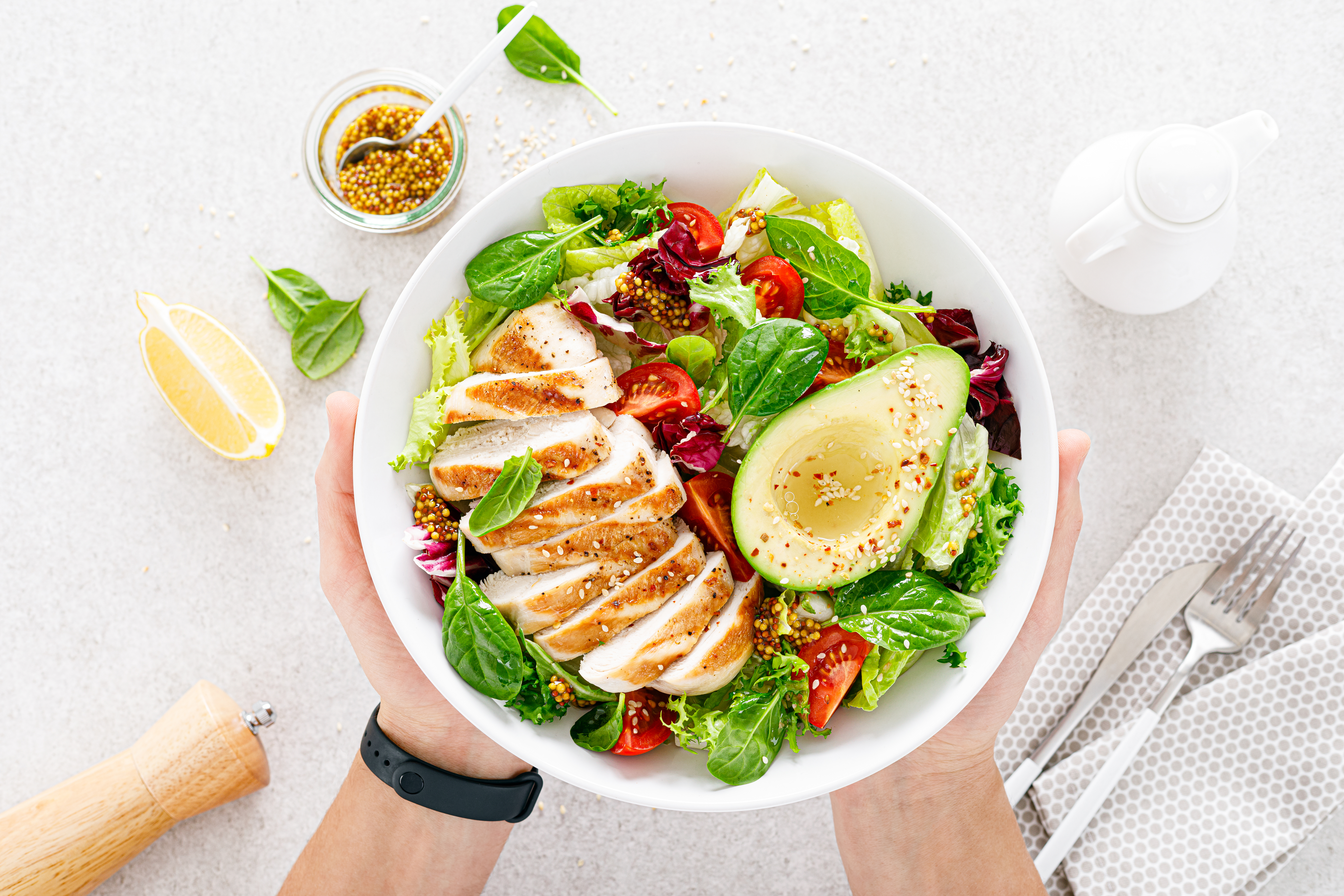 grilled-chicken-meat-fresh-vegetable-salad-tomato-avocado-lettuce-spinach-healthy-detox-food-concept-ketogenic-diet-buddha-bowl-hands-white-background-top-view